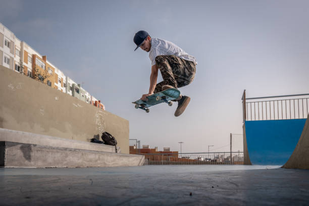 молодой фигурист делает трюк под названием бескостный. скейтбординг - skate стоковые фото и изображения