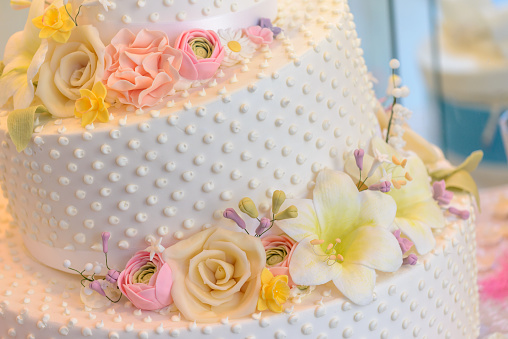 beige wedding cake with roses and ribbons close-up