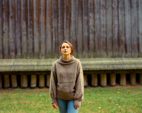 Portrait of  young Caucasian woman in brown sweater in village