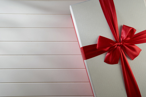 White gift card tied with red colored bow tie on white background