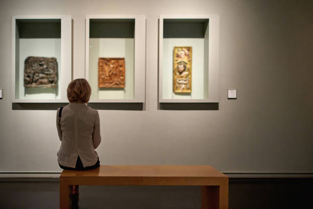 bakifrån av kvinna som sitter i ett konstgalleri framför färgglada målningar - konstmuseum bildbanksfoton och bilder
