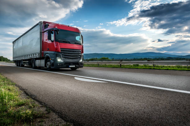 istock Red semi trailer lorry truck passing on a highway at sunset 1278747609