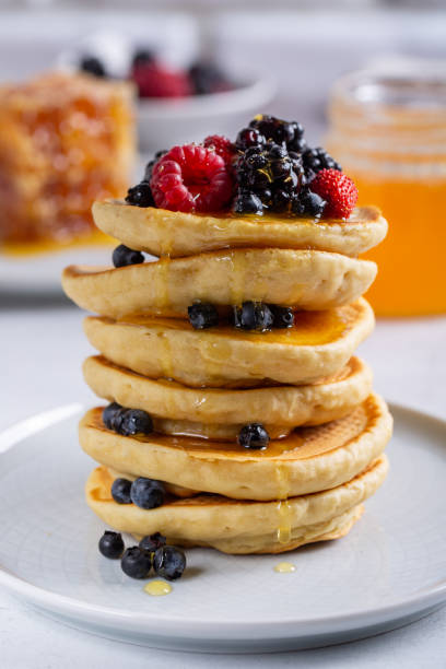 istock Pancakes with fresh berries and honey on white table. Close-up. 1278748572