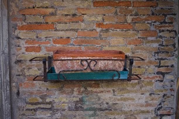 istock An empty clay pot with wrought iron decorations hanging on a ruined brick wall (Corinaldo, Marche, Italy, Europe) 1278752319