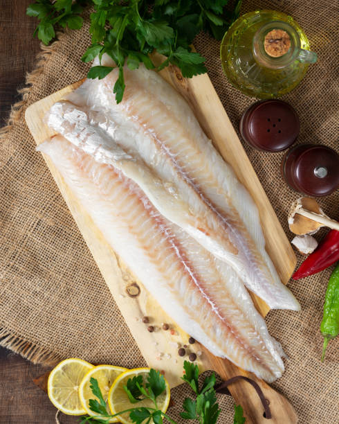 istock Cod fillet. Raw cod fillet on a chopping board on a brown kitchen table. Preparation for cooking fish. Top view 1278753192