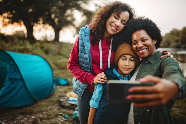 glückliche familie von drei, die selfie in der nähe ihres campingplatzes - telephone nature mobile phone autumn stock-fotos und bilder