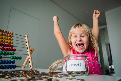 happy cute girl saving money, kid counting coins, financial literacy for kids
