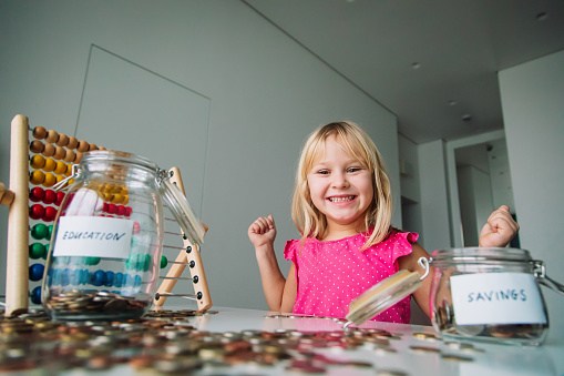happy cute girl saving money, kid counting coins, financial literacy for kids