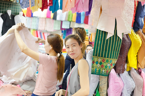Chinese woman is shopping at Khua Din Market in Shopping. Market has several sections from food to fashion and household things. Market is big and central one near Khounvieng Road. Woman is shopping traditional fashion, A vendor woman is in background