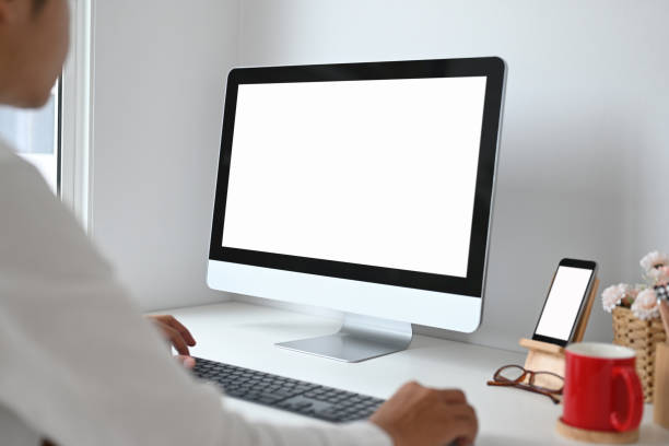 istock Cropped shot of young man working with computer and smart phone with white screen on work space. 1278756654