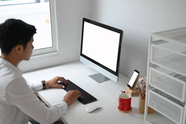 istock Young businessman typing on keyboard and using computer pc and smart phone with blank screen in home office. 1278756680