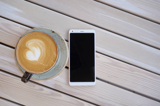 Young cheerful woman sitting in coffee shop and enjoying her time while using mobile phone and placing her photo on social network.