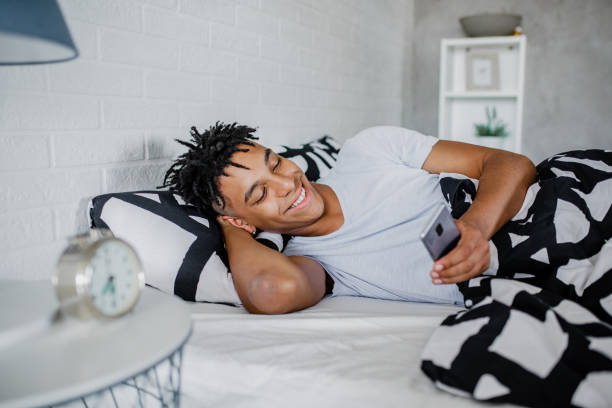 istock Young African-American man is using mobile phone in bed 1278760302