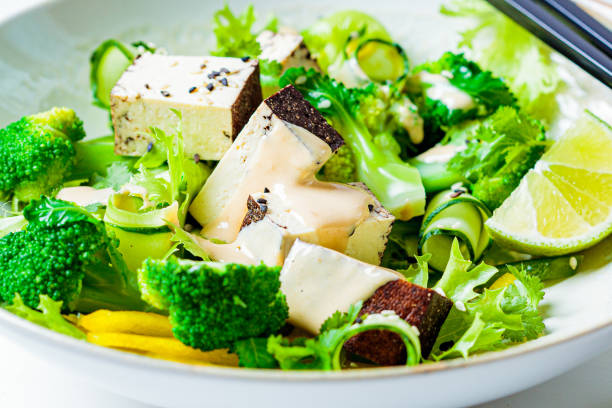 브로콜리, 훈제 두부, 땅콩 드레싱을 화이트 볼, 흰색 배경이 있는 녹색 아시아 샐러드. - tofu chinese cuisine vegetarian food broccoli 뉴스 사진 이미지