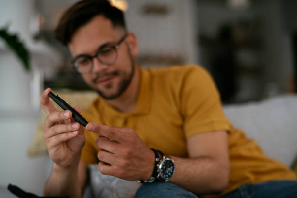 istock Diabetic man taking blood sample with lancet pen at home. 1278766125