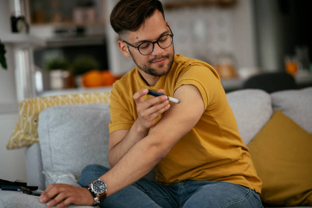 Young man giving himself an insulin shot at home. Young man giving himself an insulin shot at home. medical injection photos stock pictures, royalty-free photos & images
