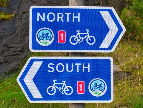 Two white on blue signs for the UK National Cycle Route 1 in Lerwick, Shetland, Scotland, UK - one pointing North, the other pointing South.