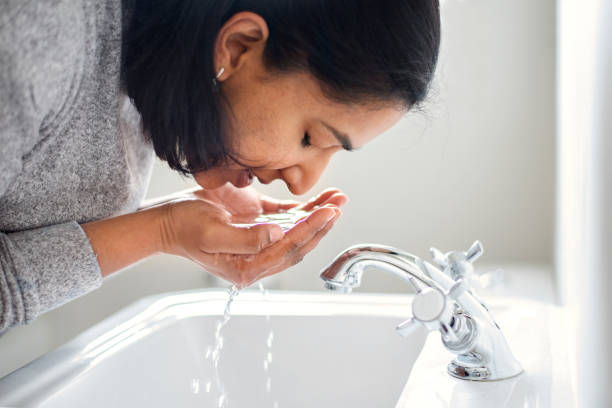 istock Woman washing her face over her bathroom sink 1278768026