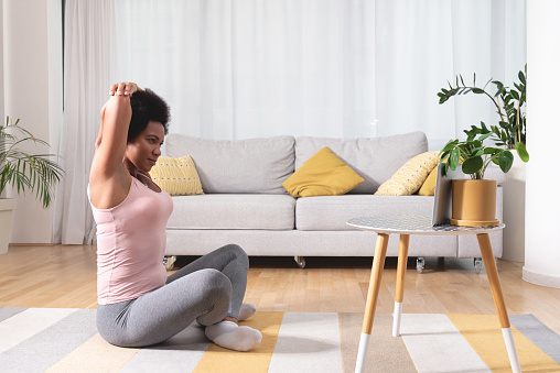 Woman stretching as shown online on digital tablet