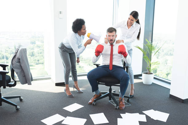 Two female colleagues encouraging a man to win office battle Two female colleagues encouraging a man to win office battle business battle stock pictures, royalty-free photos & images