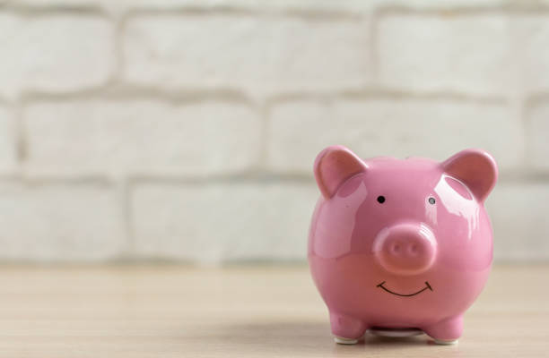 istock Pink piggy Bank on a table or shelf against a light brick wall. 1278772427