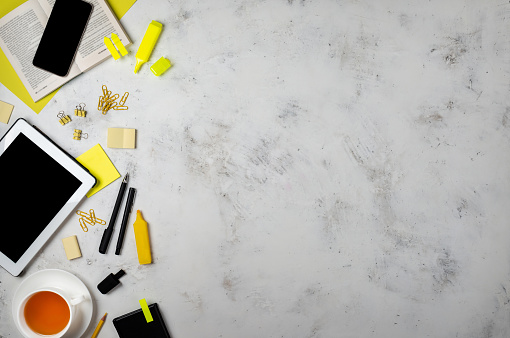 Office supplies in yellow colours and gadgets on the desk background. Top view with copy space.