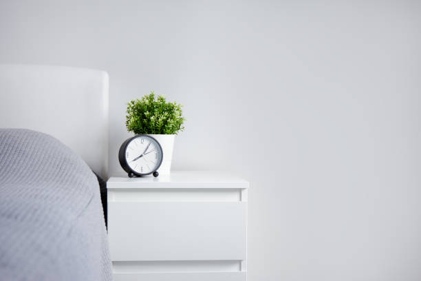 istock good morning concept - alarm clock and houseplant on bedside table and copy space over white wall 1278774841