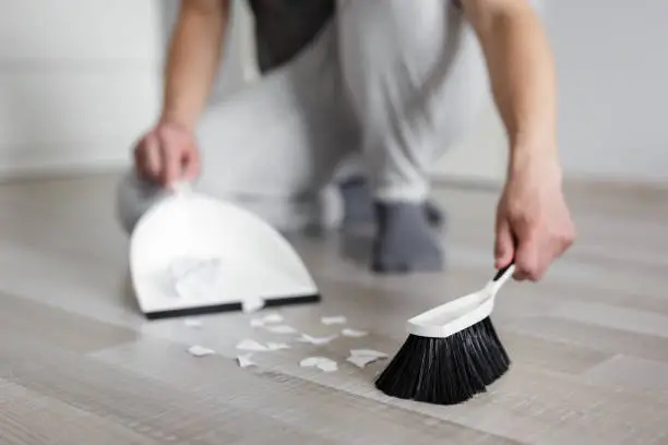 Photo of male hands cleaning ripped pieces of paper with scoop and brush