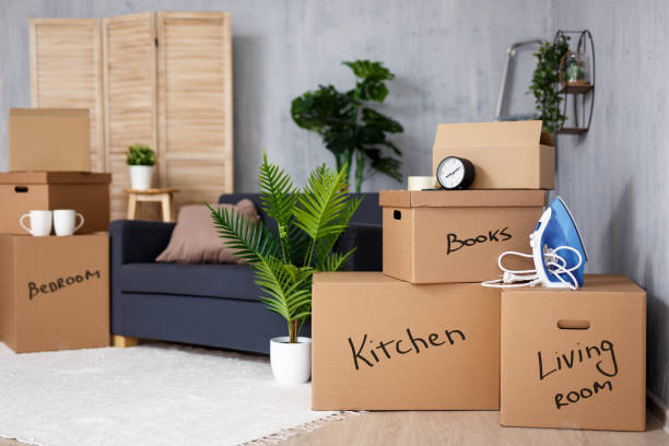 moving to new house - cardboard boxes with belongings stacked in living room after moving day stock photo