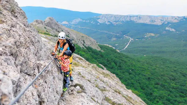 Photo of Mother, child in safety equipment climb by via ferrata route