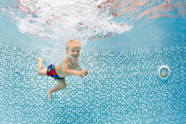 lycklig barn dyka under vattnet med kul i swimmingpool - baby swim under water bildbanksfoton och bilder