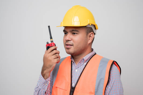 istock Asian civil engineer operate with radio walkie talkie to control working in studio. Worker wearing hard hat standing on isolated white background. 1278776422