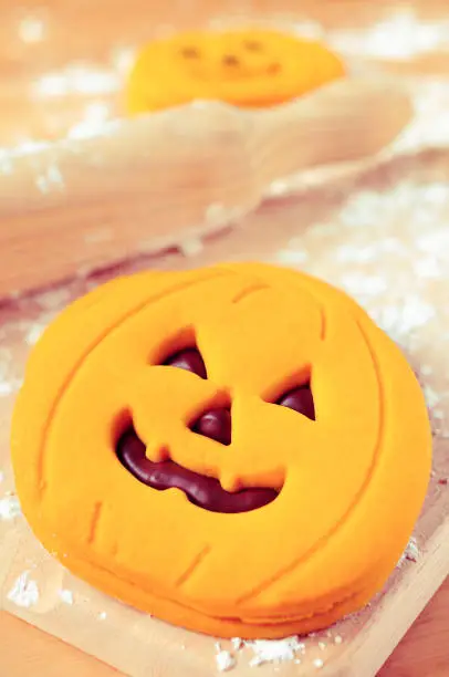 some cookies in the shape of jack-o-lanterns on a table sprinkled with wheat flour