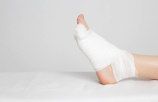 Man's bandaged foot with little finger on a white background. The concept of a fracture of the little finger on the leg with offset, copy space