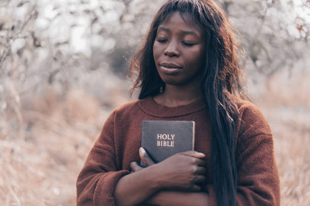 chica afro cristiana tiene la biblia en sus manos. leyendo la santa biblia - christian mujer leyendo la biblia fotografías e imágenes de stock