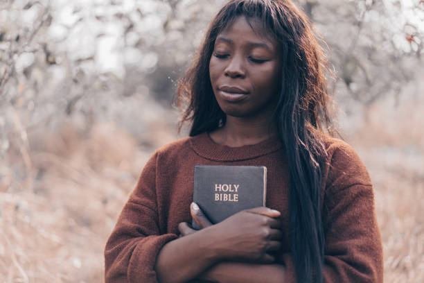 christian afro girl holds bible in her hands. reading the holy bible - women human hand portrait eyes closed imagens e fotografias de stock