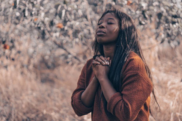 afro girl zamknęła oczy, modląc się na świeżym powietrzu. ręce złożone w koncepcji modlitewnej dla wiary, duchowości i religii - please god zdjęcia i obrazy z banku zdjęć