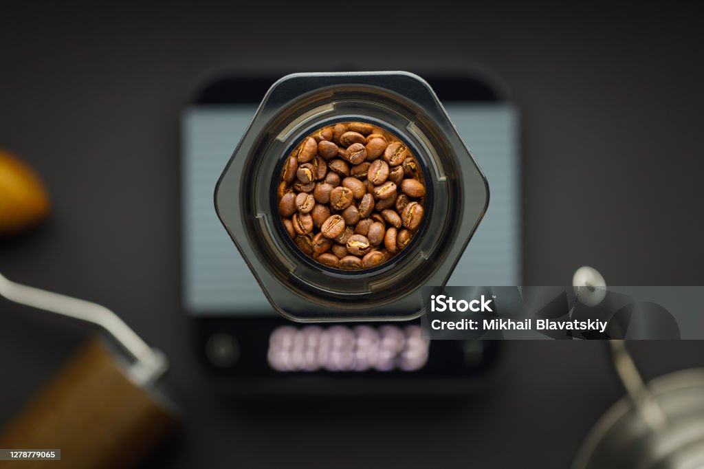 Aeropress coffee maker with scales, coffee grinder and kettle on a black background top view. Aeropress coffee maker with scales, coffee grinder and kettle on a black background top view. Aeropress with coffee beans in focus, background blurred. Brewery Stock Photo