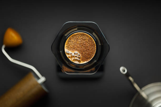 Aeropress coffee maker with scales, coffee grinder and kettle on a black background top view.