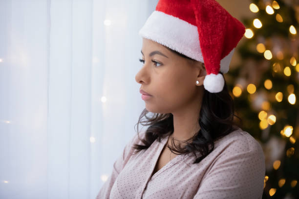 femme biraciale bouleversée se sentent seuls la veille du nouvel an - holiday emotional stress christmas santa claus photos et images de collection
