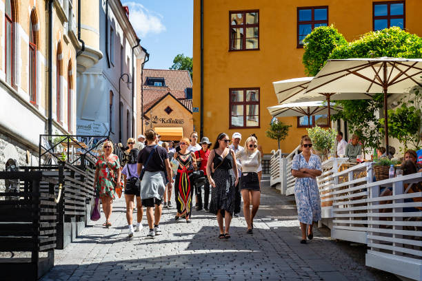 Group of attractive young women walking down narrow medieval street in Visby, Gotland, Sweden stock photo