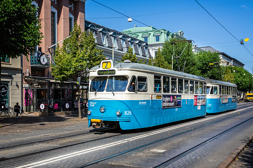 Blue and white electric tram pulling in to tram stop in Gothenburg, Sweden on 26 July 2019