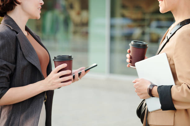 istock Two young successful contemporary businesswomen with drinks and gadgets 1278787414