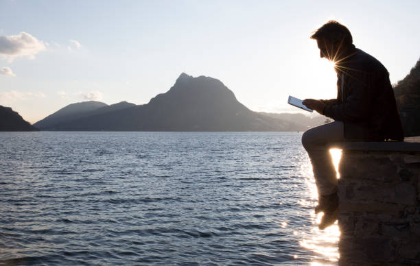 istock Man uses digital tablet by a lake at sunrise 1278787602