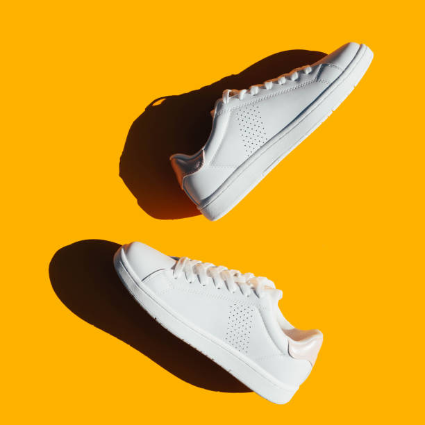 istock White sneakers on an orange background with hard shadows. 1278798817
