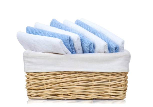 Towels in the laundry basket. Blue and pink cotton terry towels are thrown into a pink plastic basket. Housekeeping. Storing and separating laundry before washing. Light from above from an open window
