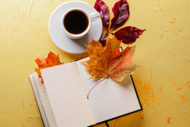istock Autumn coffee. A cup of espresso, a blank notepad and fall foliage on a yellow concrete table. Flat lay. Copy space 1278799009
