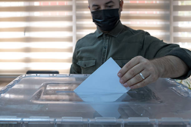 masked man voting, the citizenship duty to vote in the election. stock photo