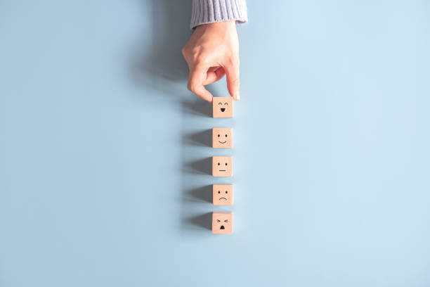 istock Customer service evaluation and satisfaction survey concepts. The client's hand picked the happy face smile face icon symbol on wooden cube. 1278803402