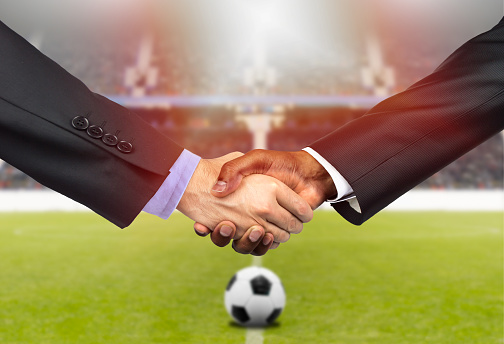 Cropped shot of two business people shaking hands together indoors on the soccer court